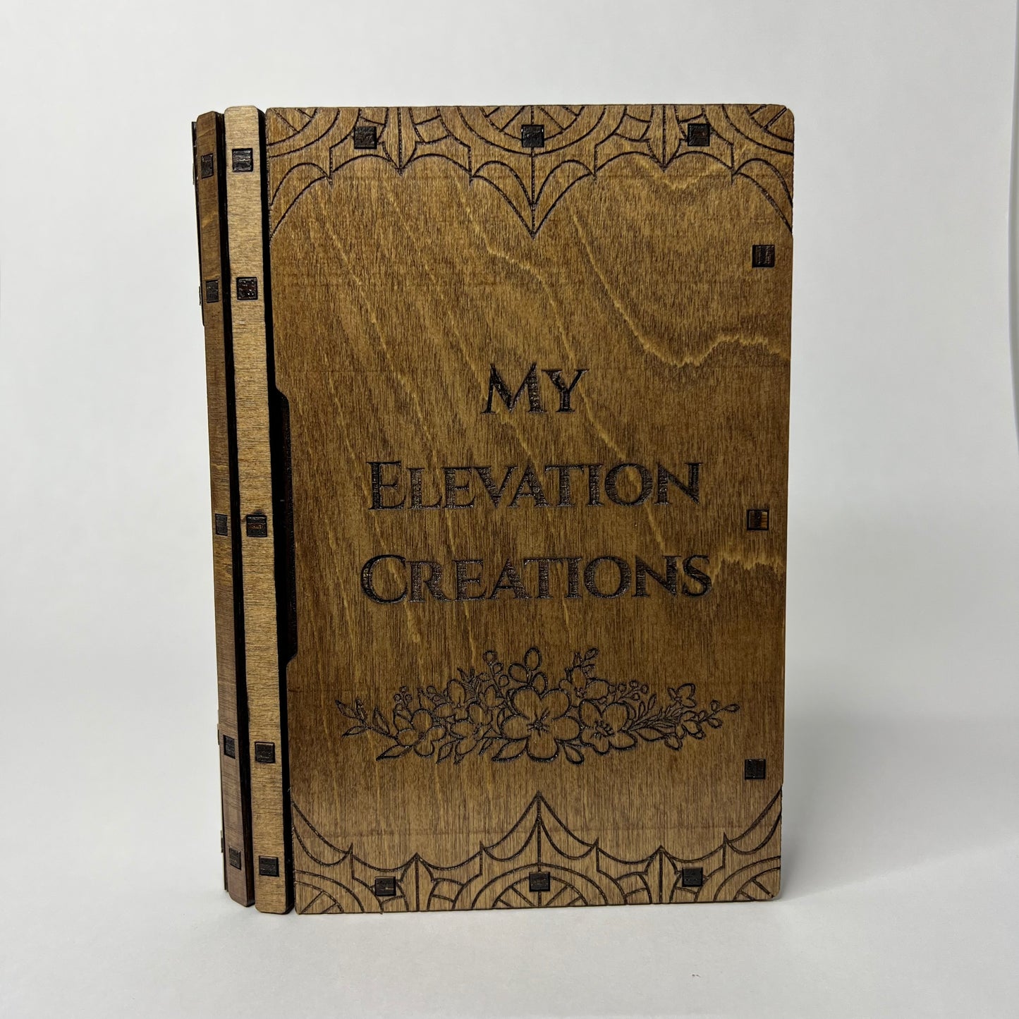 Front cover of the sliding book box with My Elevation Creations etched into the center with flowers underneath.