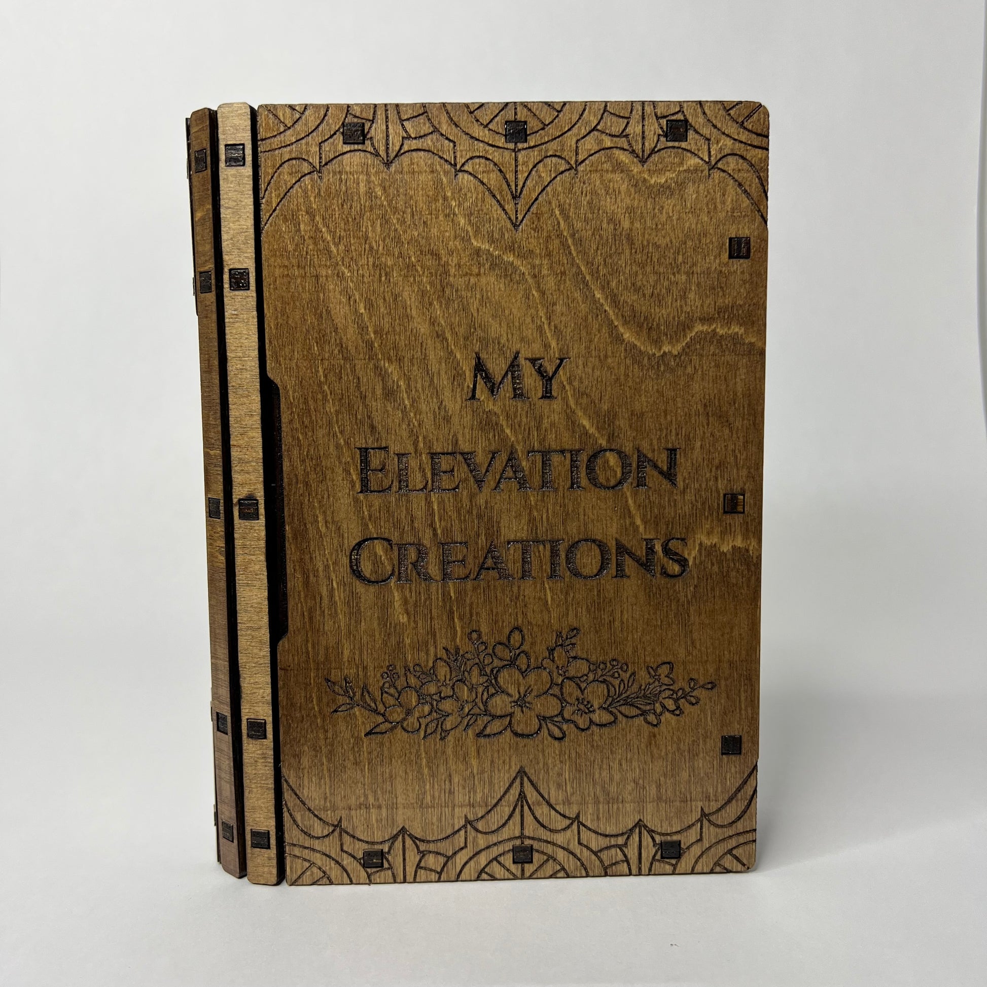 Front cover of the sliding book box with My Elevation Creations etched into the center with flowers underneath.